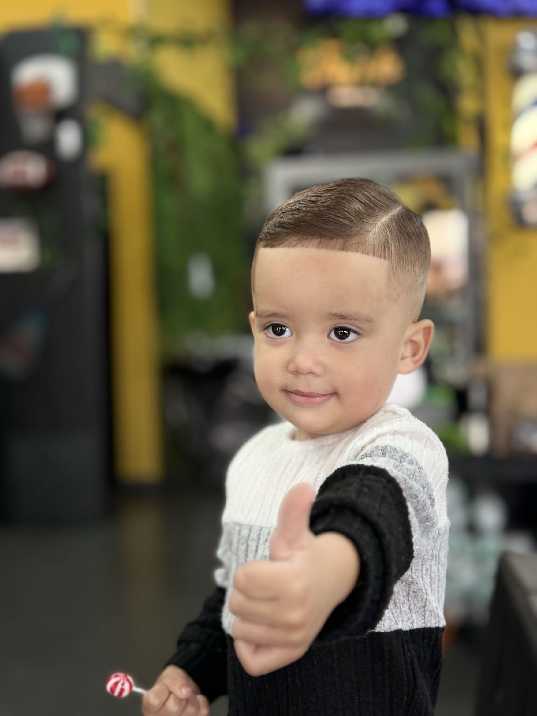 Criança com corte de cabelo e risca lateral fazendo um sinal de positivo na VNS Style